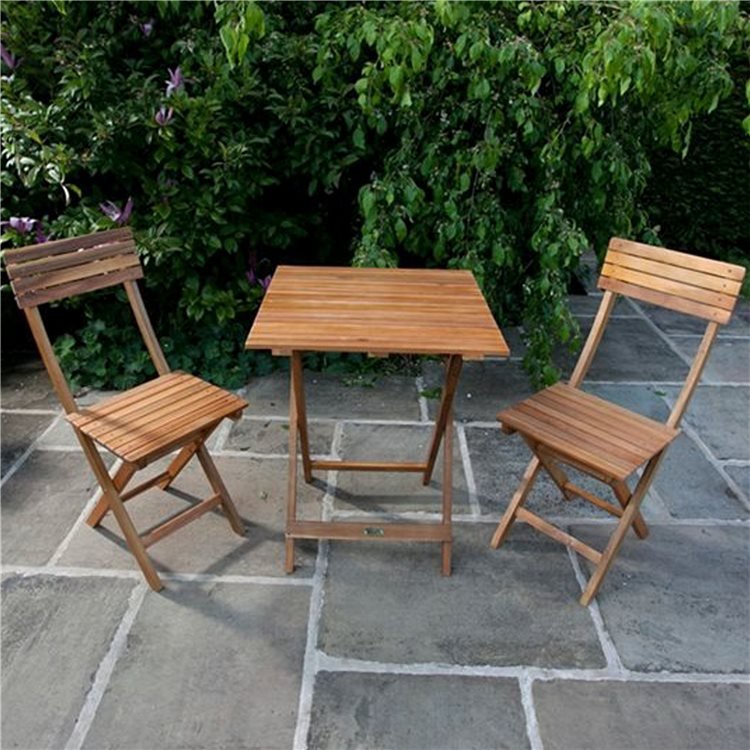 Wooden bistro set with two chairs and a table on a dark gray paved patio